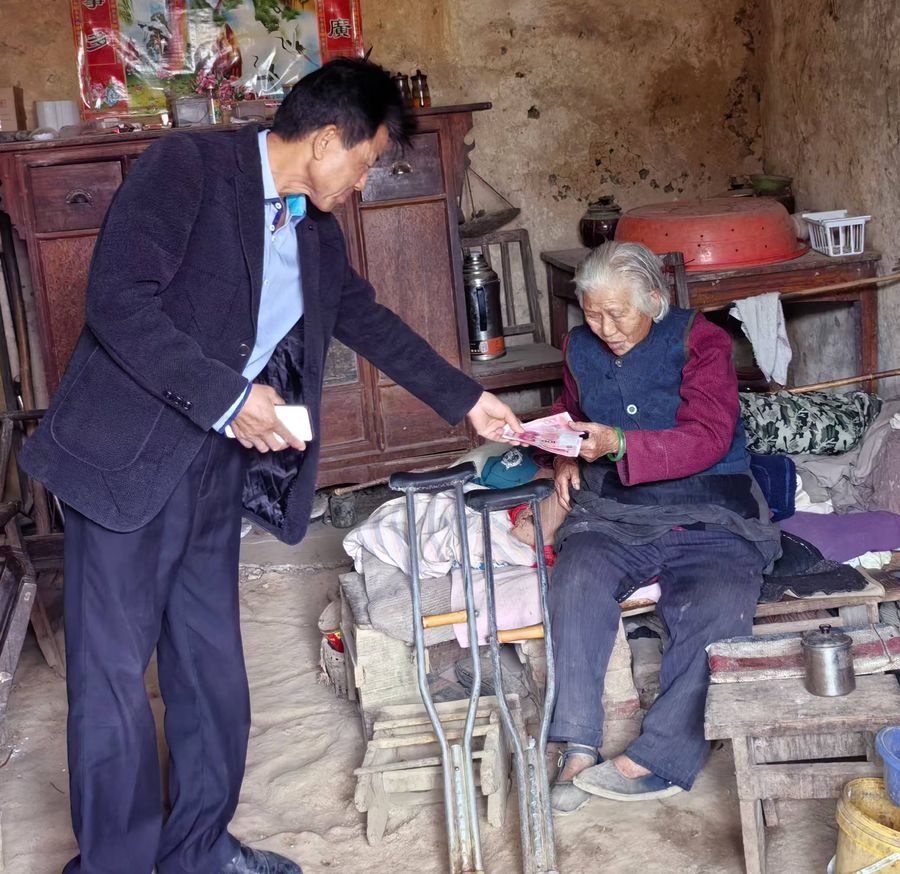 The monthly stipend being handed to an elderly villager in her home